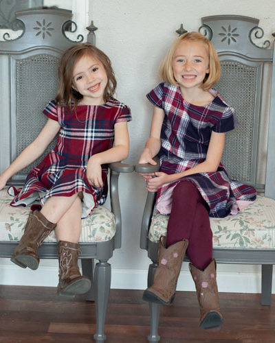 Girls in chair wearing plaid dresses.